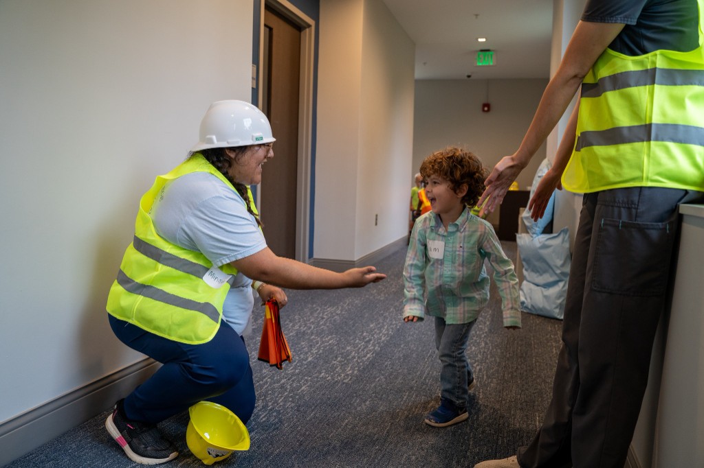 OT student greeting a child in the hallway with open arms.