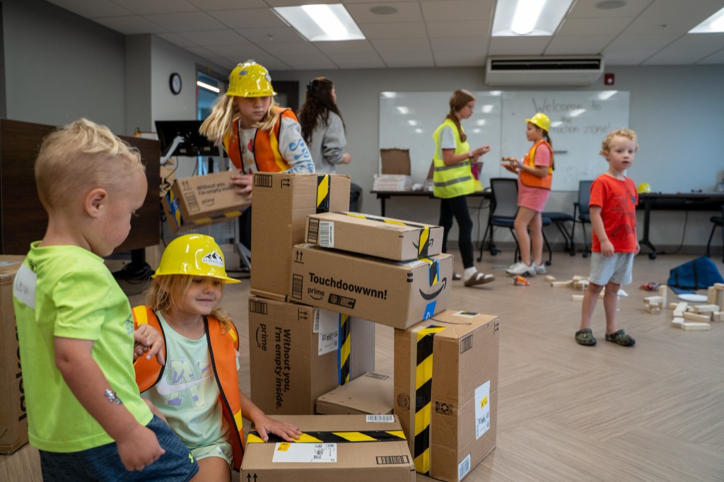 Children collaborating to stack and balance cardboard boxes.